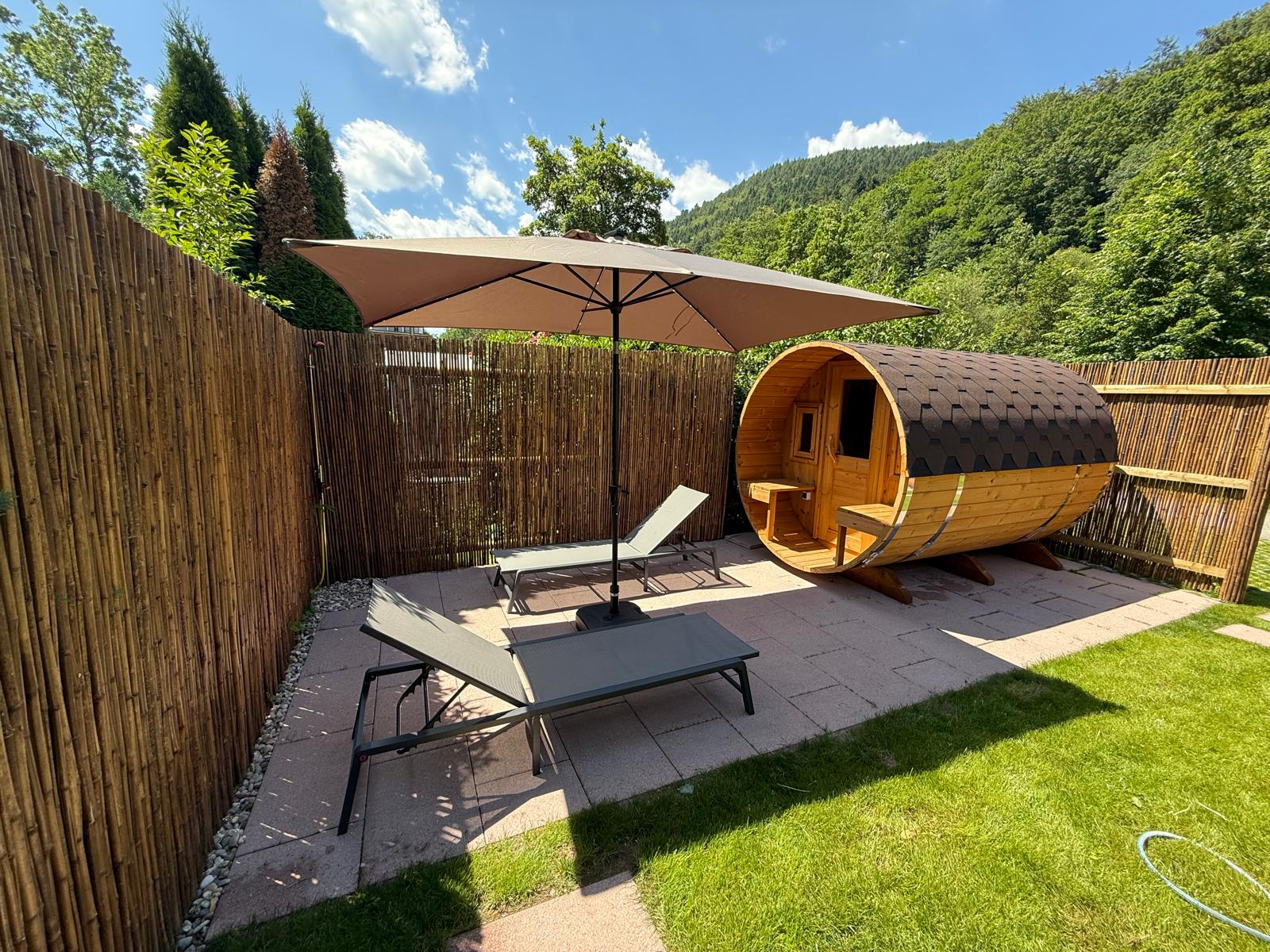 Sauna tonneau avec transats et parasol dans le jardin
