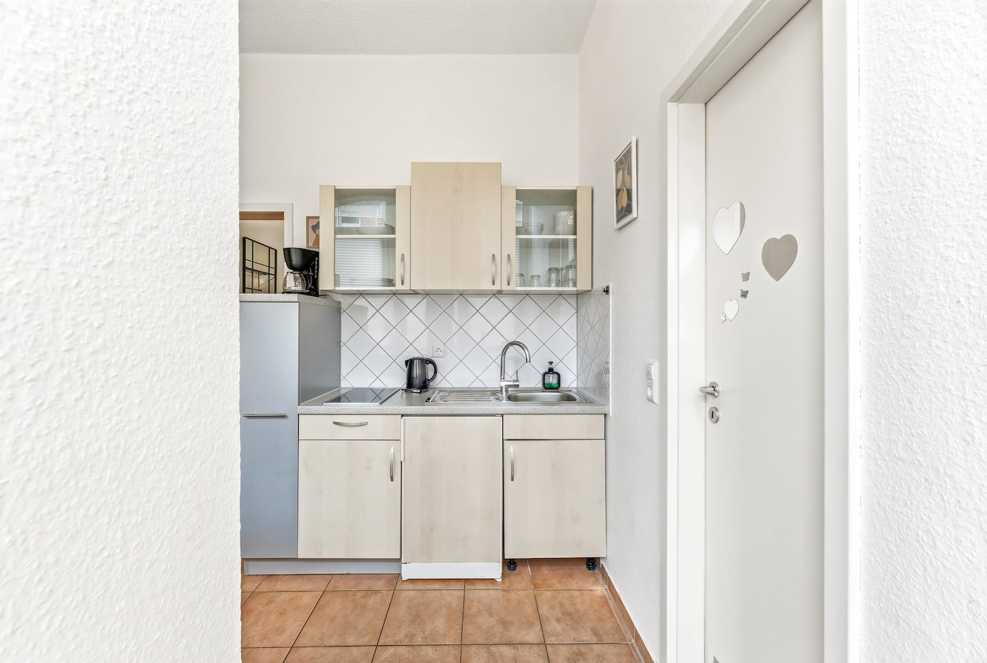 Kompakte Küchenzeile mit Kochfeld, Kühlschrank und Kaffeemaschine
