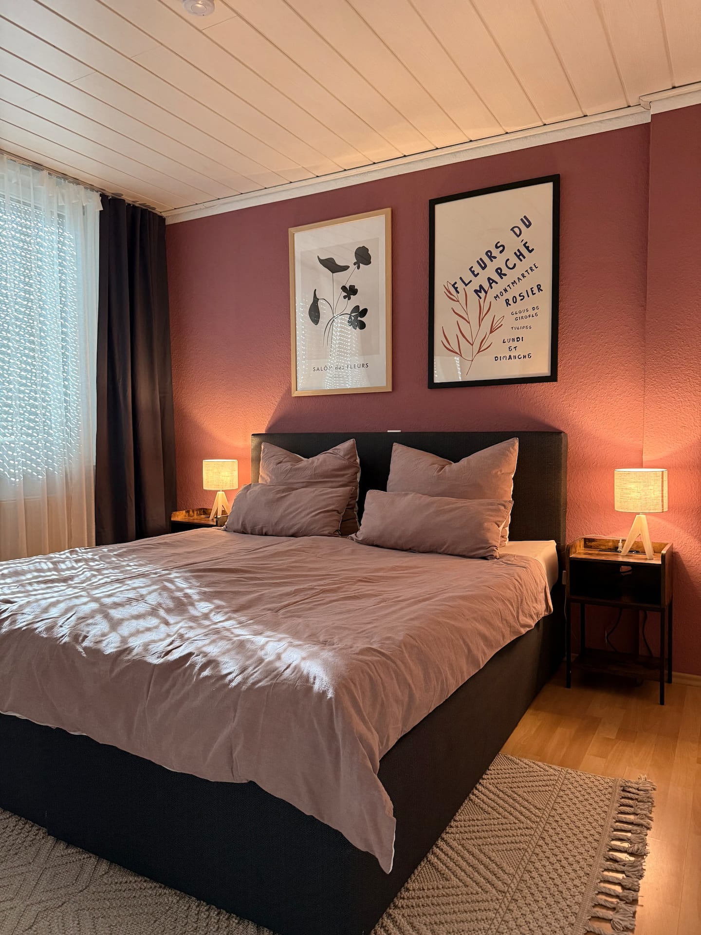 Schlafzimmer mit Doppelbett vor warmer altrosa Akzentwand