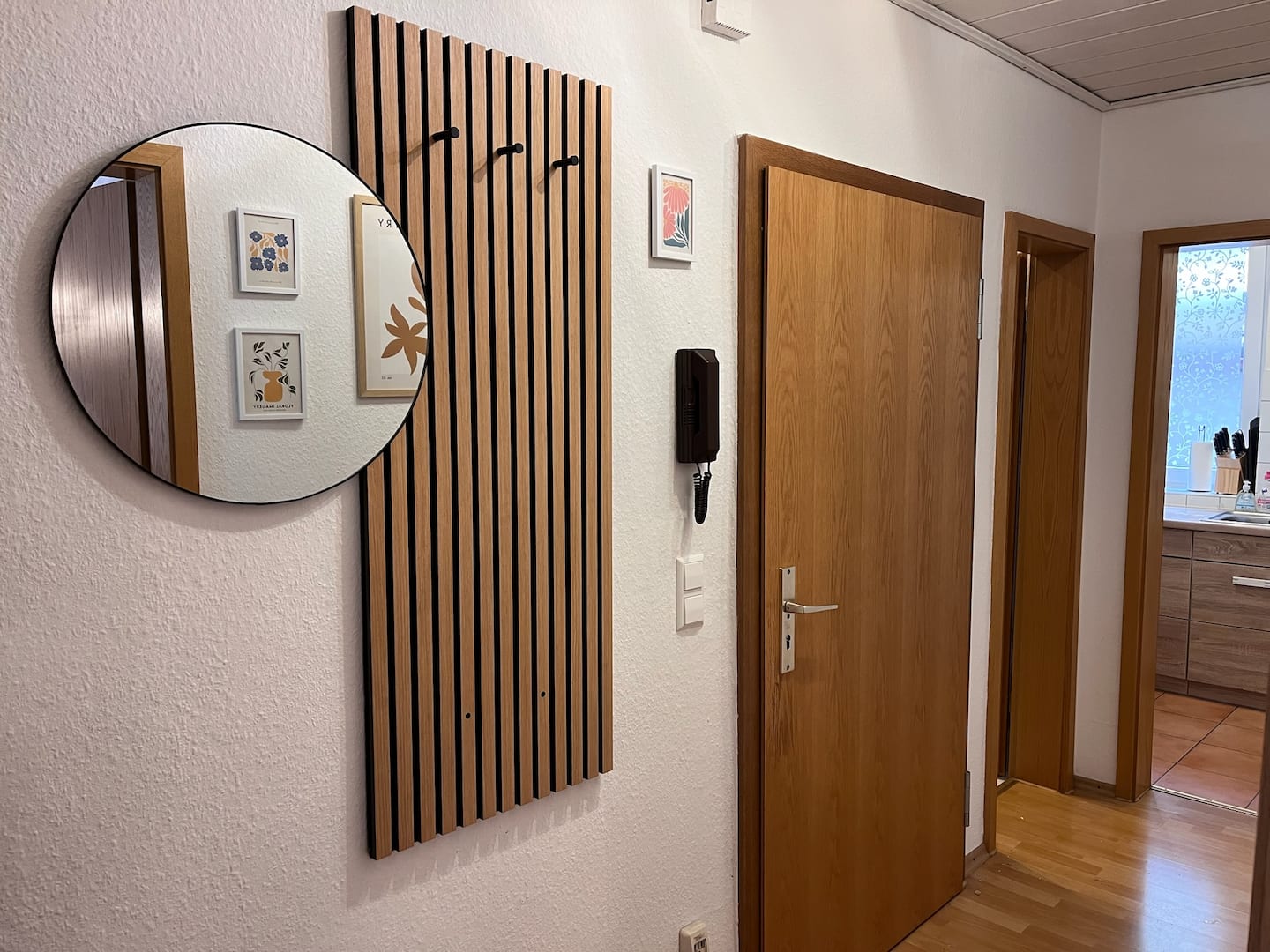 Einladender Flur mit rundem Spiegel und Holzlamellen-Wand