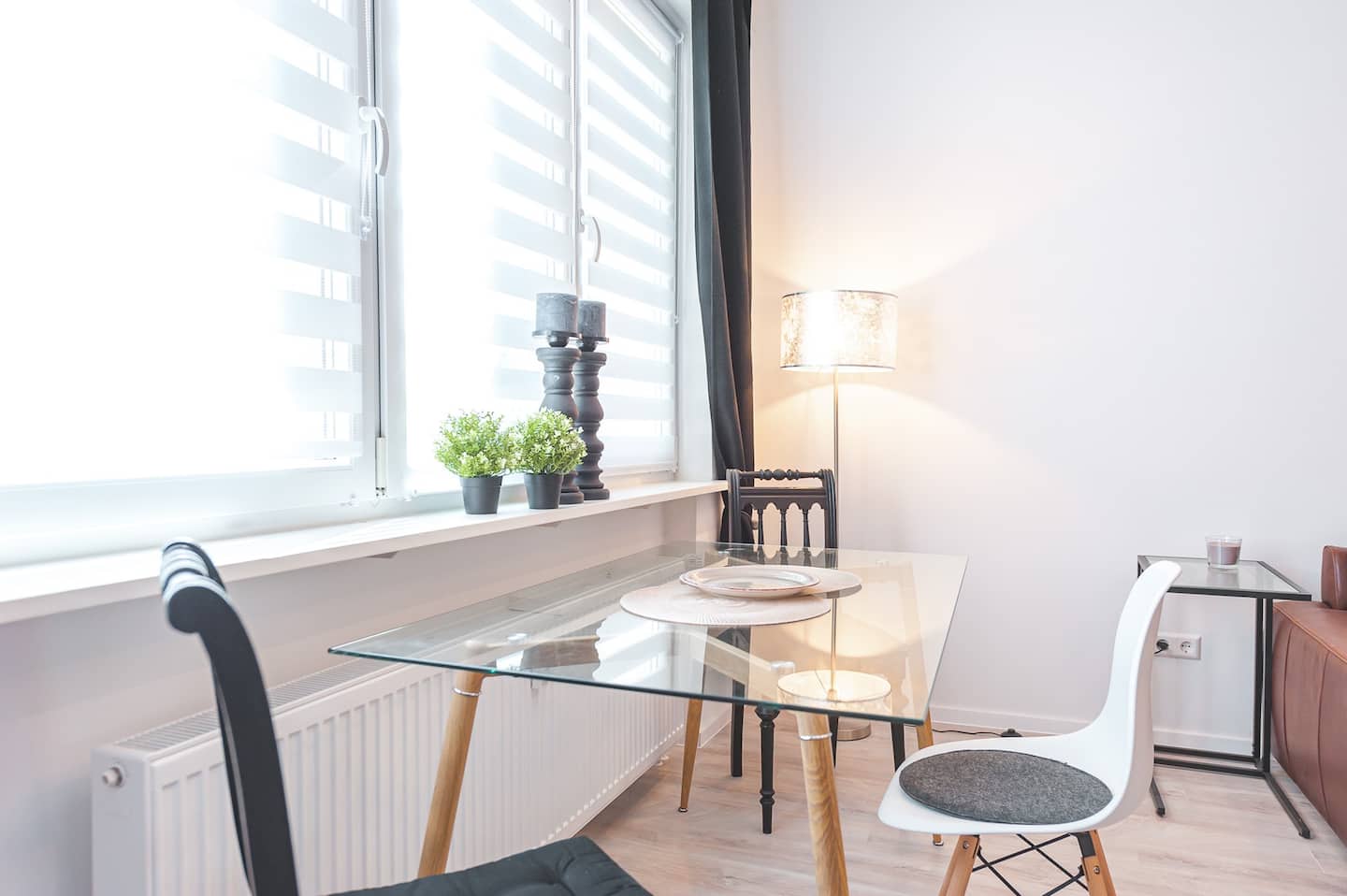 Essplatz mit Glastisch, Designerstühlen und Stehleuchte am Fenster