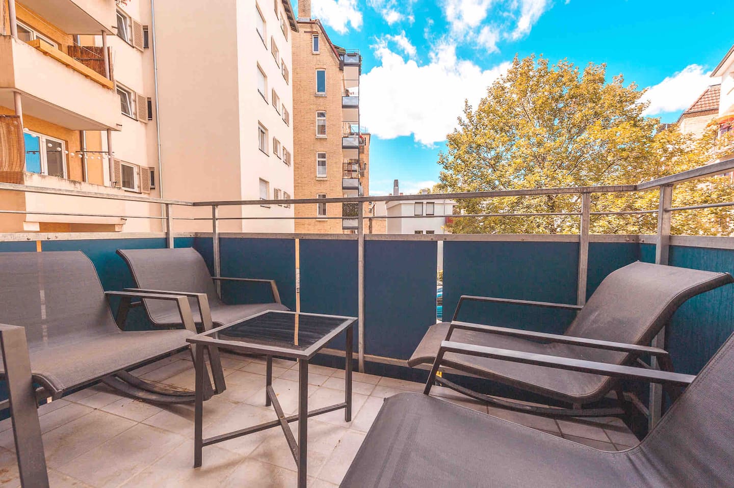 Eigener Balkon mit zwei Sonnenliegen und Blick ins begrünte Viertel