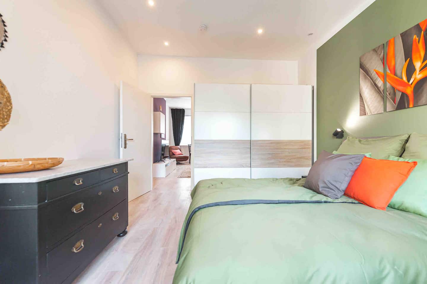 Schlafzimmer mit großem Kleiderschrank, Kommode und Blick durch zum Wohnbereich