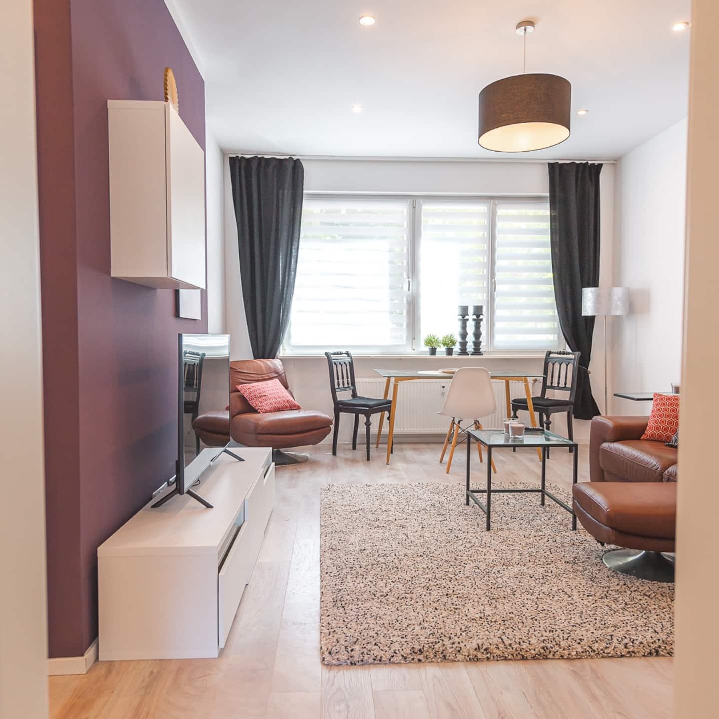 Heller Wohn- und Essbereich mit Ledersofa, Ledersessel und Esstisch am Fenster